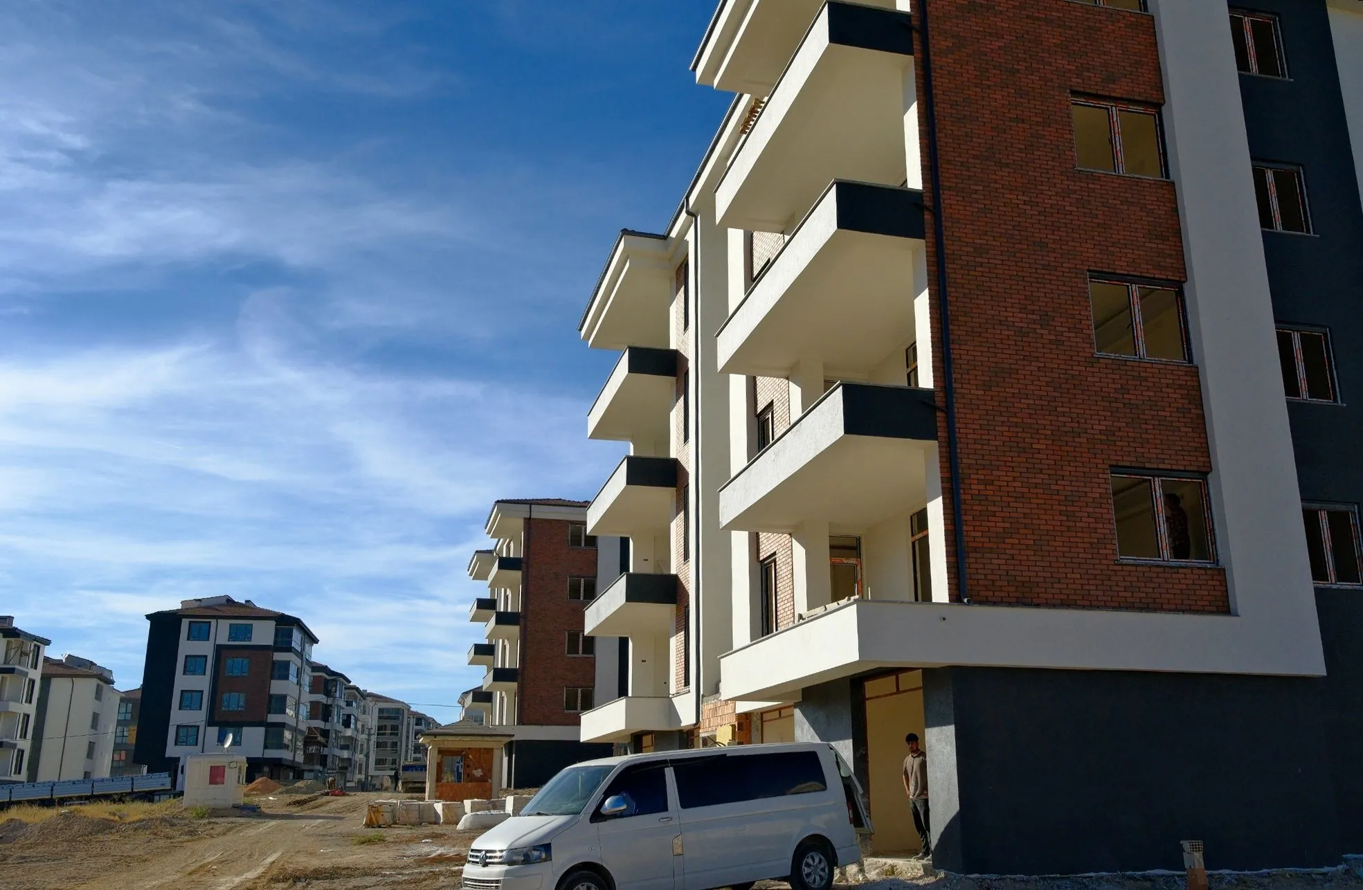 Tuğla kaplama ve antrasit balkonlu blok, yanında servis aracı